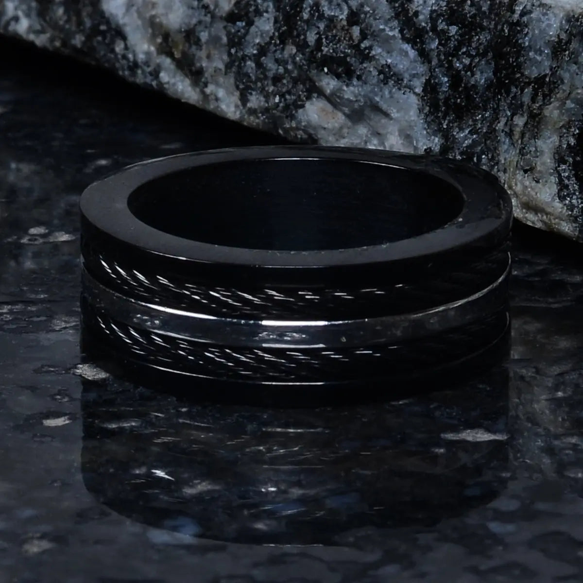 Black ring for men on a dark textured surface with a stone background by Supreme Stud