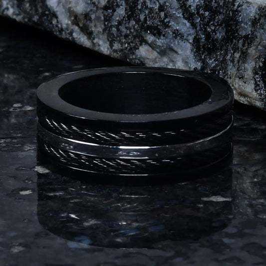 Black ring for men on a dark textured surface with a stone background by Supreme Stud