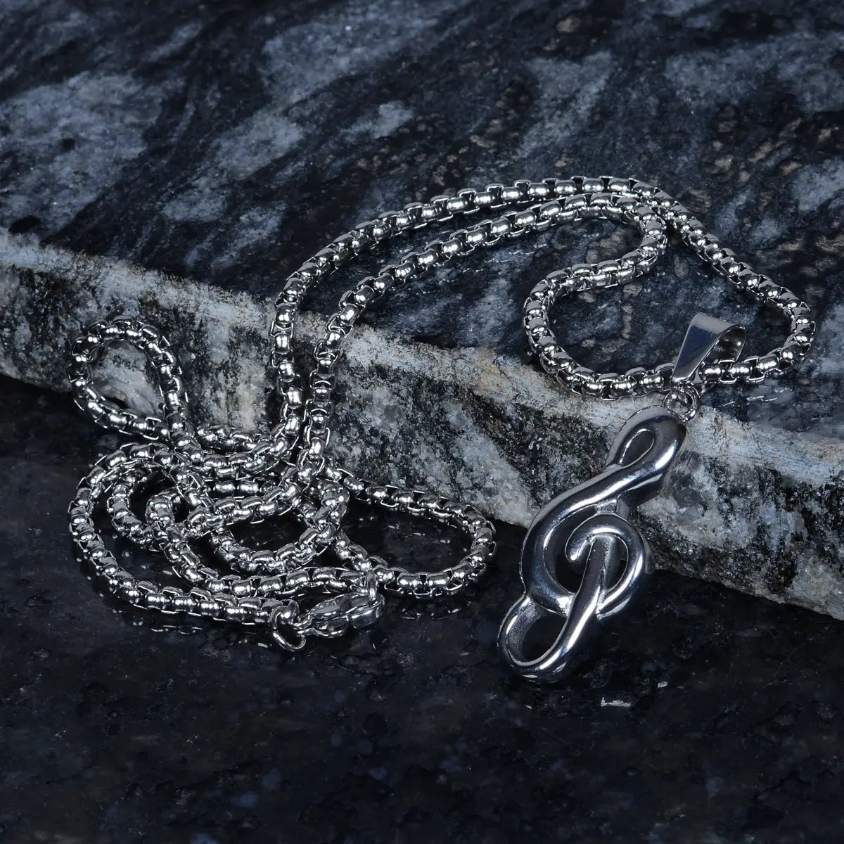 Steel chain necklace for men with a unique music pendant on a dark stone surface by Supreme Stud