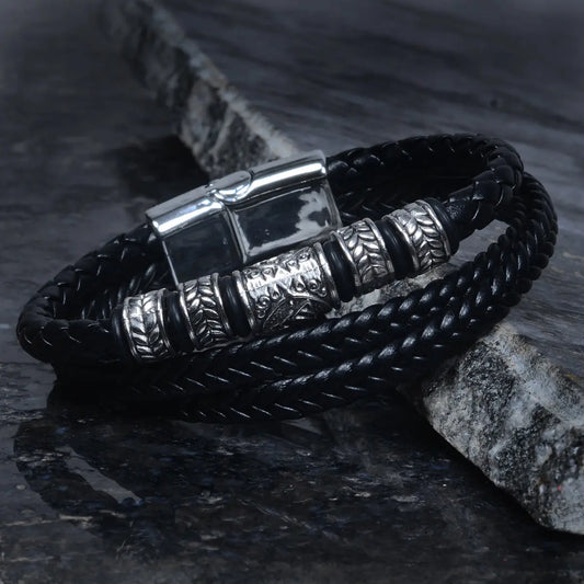 Black braided leather bracelet for men with silver metal accents on a dark stone surface by Supreme Stud