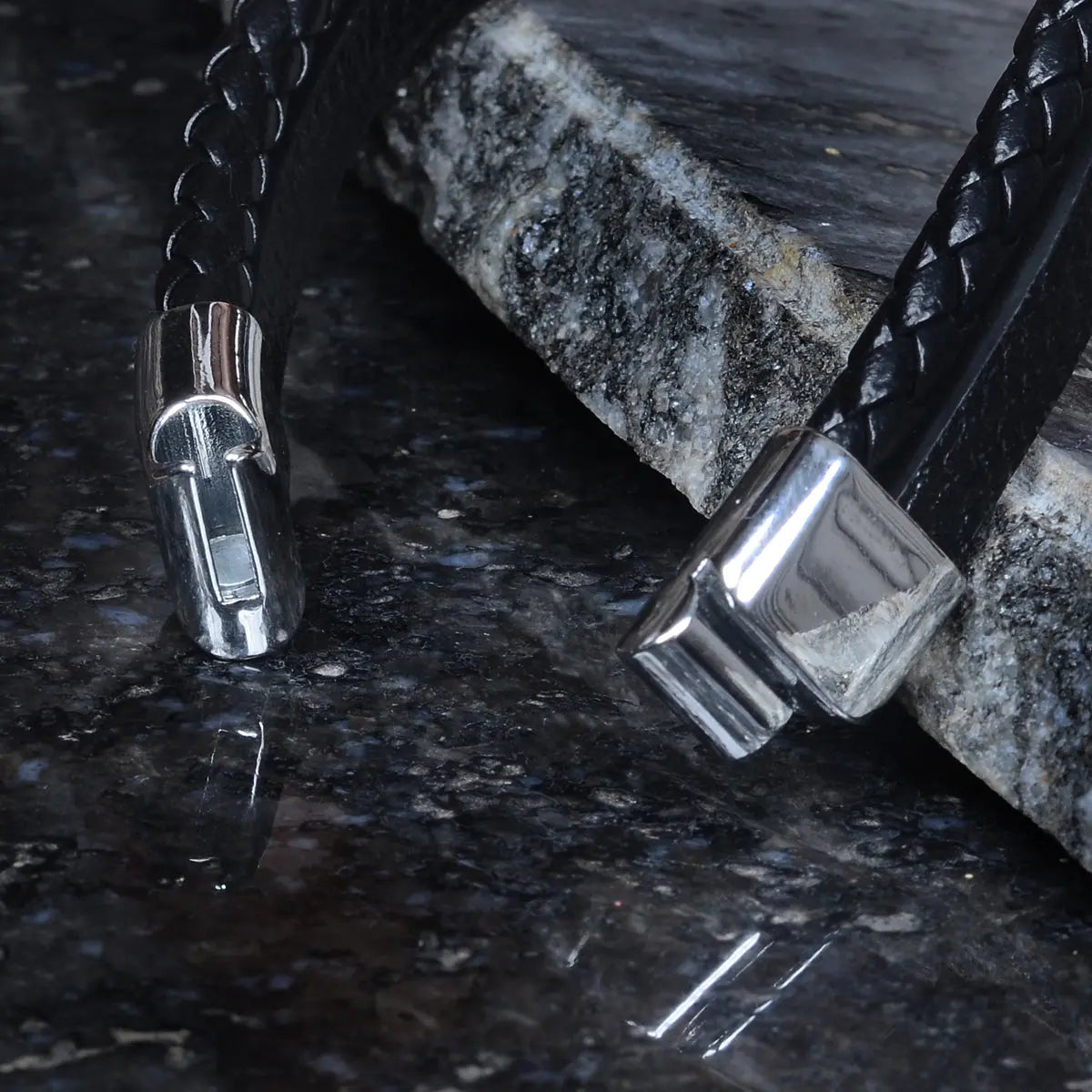 Black leather bracelet for men with silver clasp on a dark surface by Supreme Stud