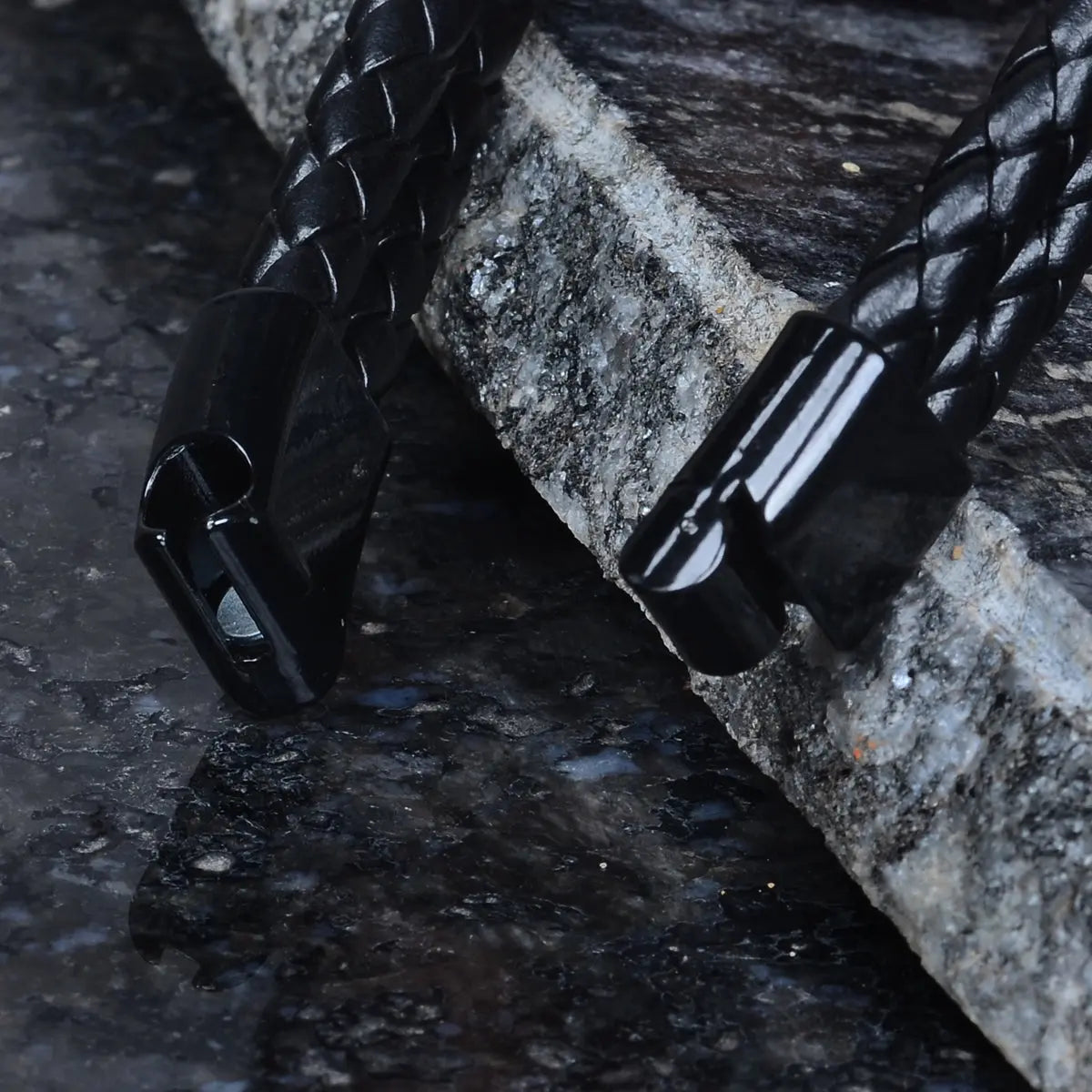 Black braided leather bracelet for men on a stone surface by Supreme Stud