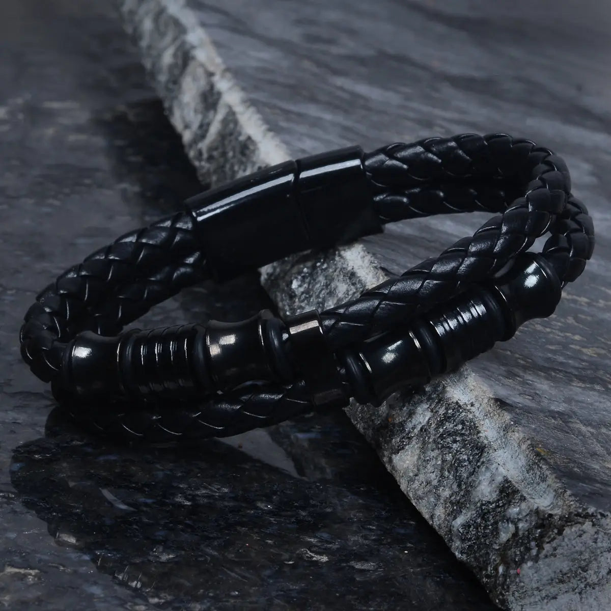 Black braided leather bracelet for men on a stone surface by Supreme Stud