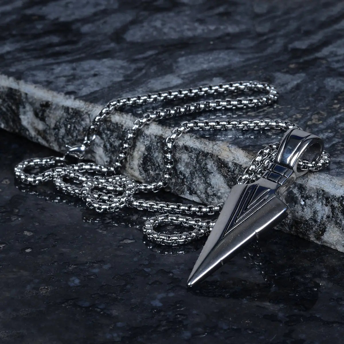 Silver necklace with a stainless steel pendant for men on a dark stone surface by Supreme Stud