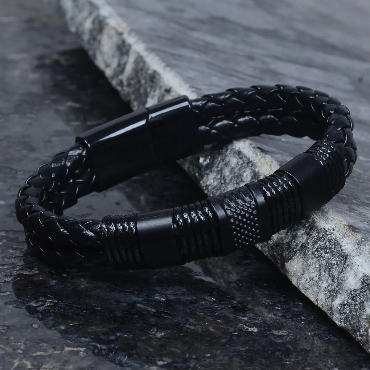 Black braided leather bracelet for men on a stone surface by Supreme Stud