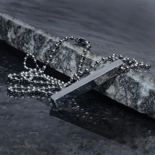 Silver necklace with a rectangular pendant for men on a stone surface by Supreme Stud